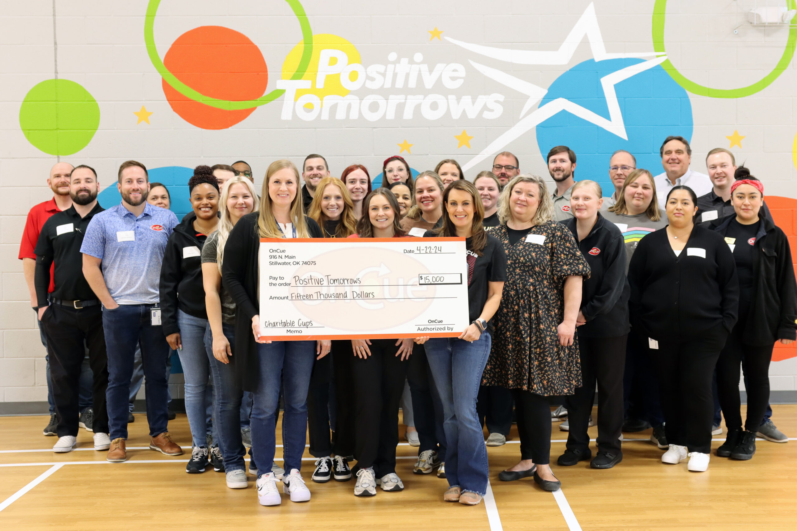 The OnCue team presents $15,000 check to Positive Tomorrows.