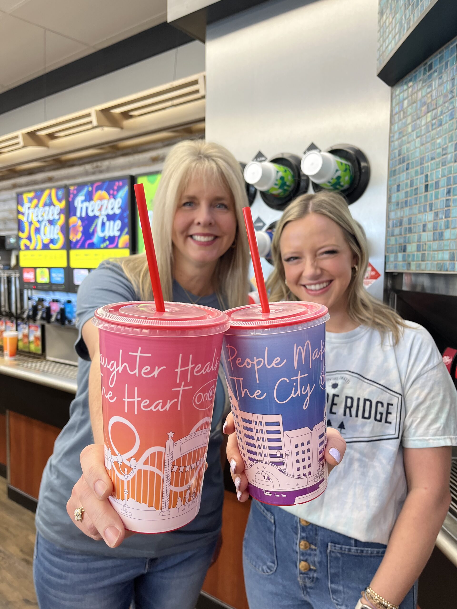Two teachers holding OnCue Fundraiser Cups.