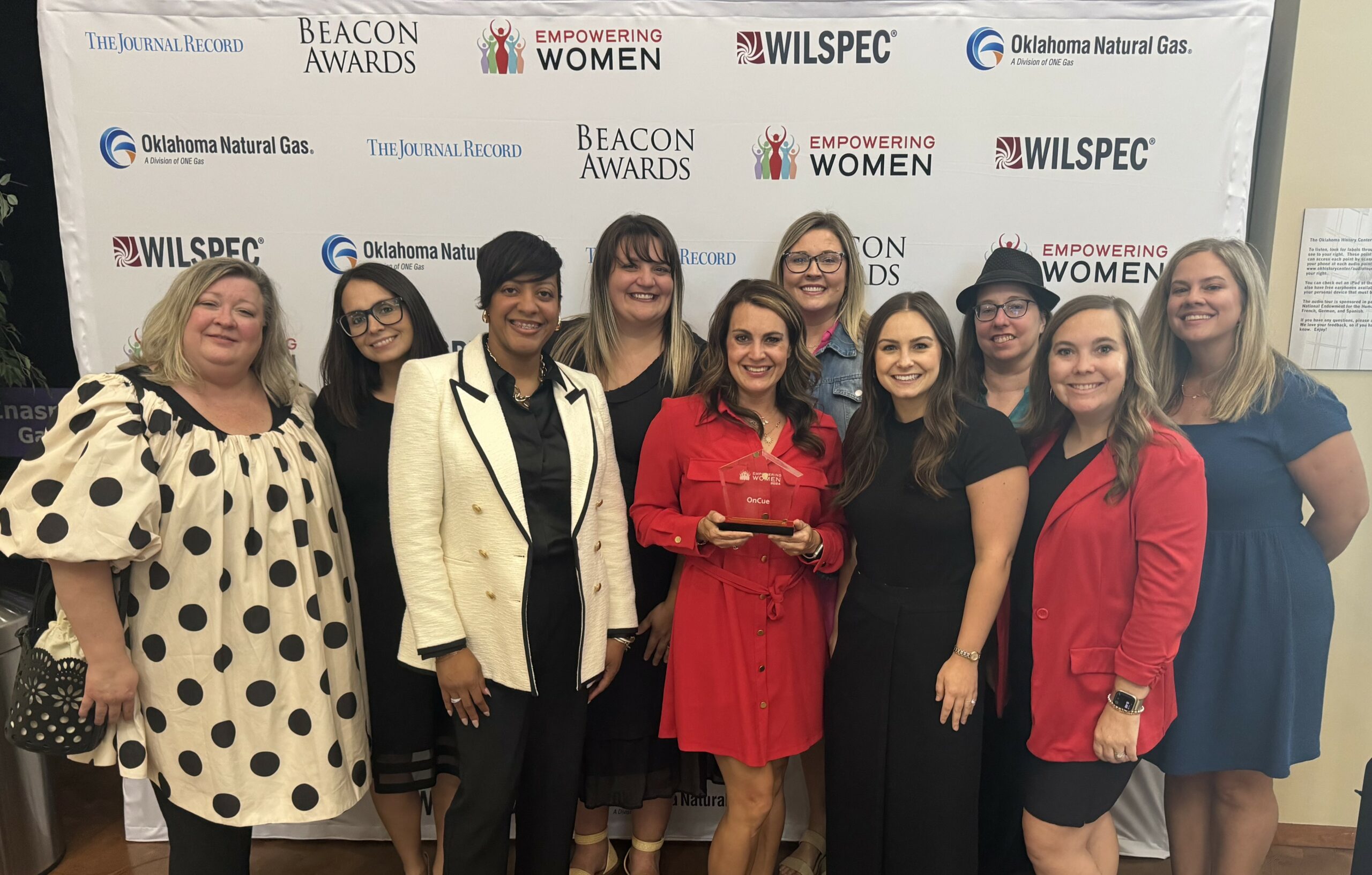 OnCue team members celebrate OnCue receiving the Empowering Women Awards from The Journal Record holding the trophy for a group photo.