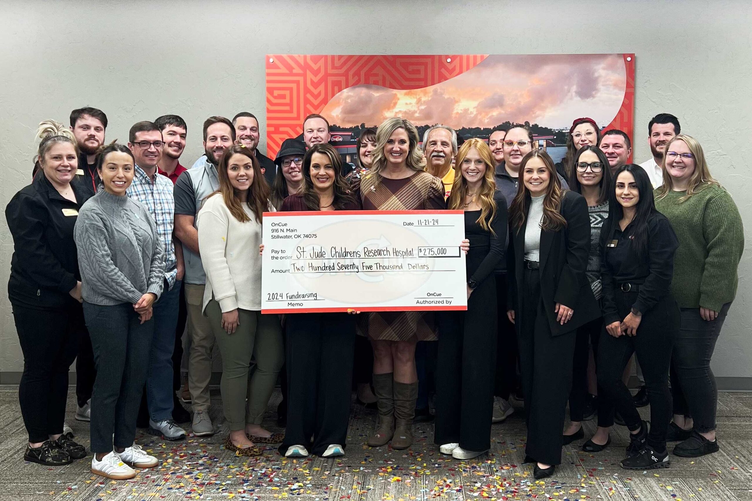 OnCue team members presenting a donation check to a St. Jude Oklahoma representative, supporting children's health initiatives.